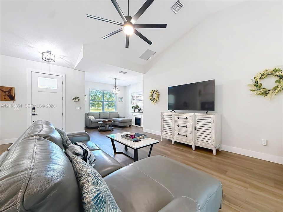 Vaulted ceilings, wood-finish flooring, multi-blade ceiling fan, and recessed lighting