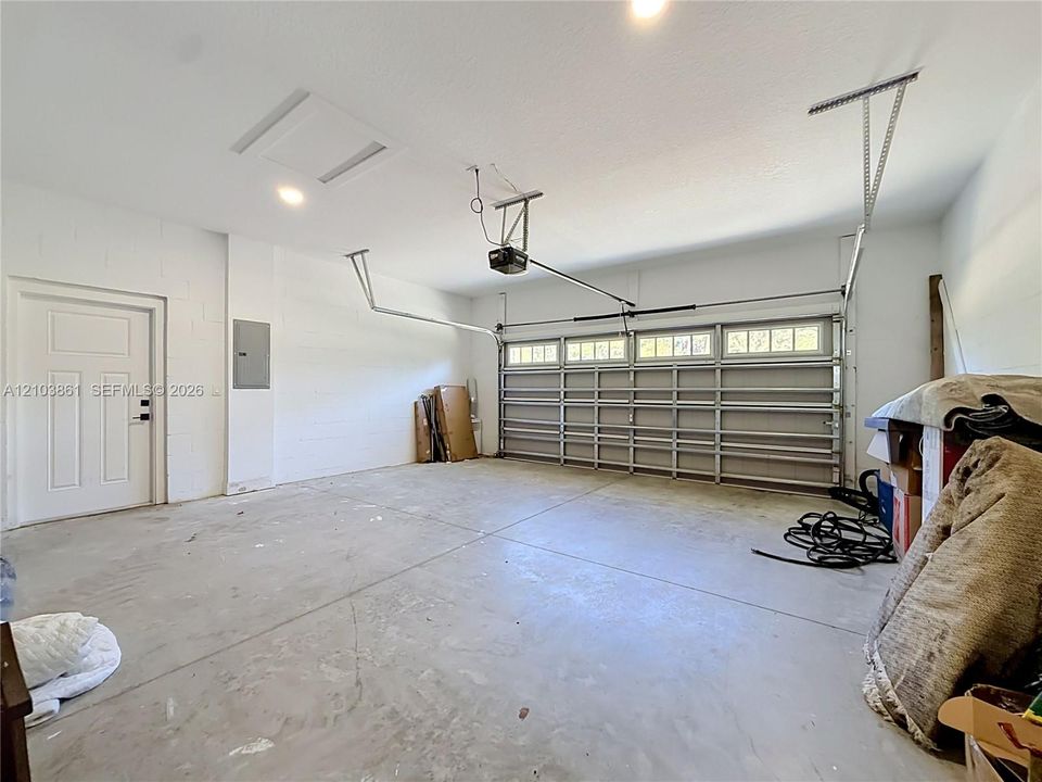 Attached two-car garage featuring a sectional door with windows, concrete flooring, painted masonry walls, and a dedicated service door