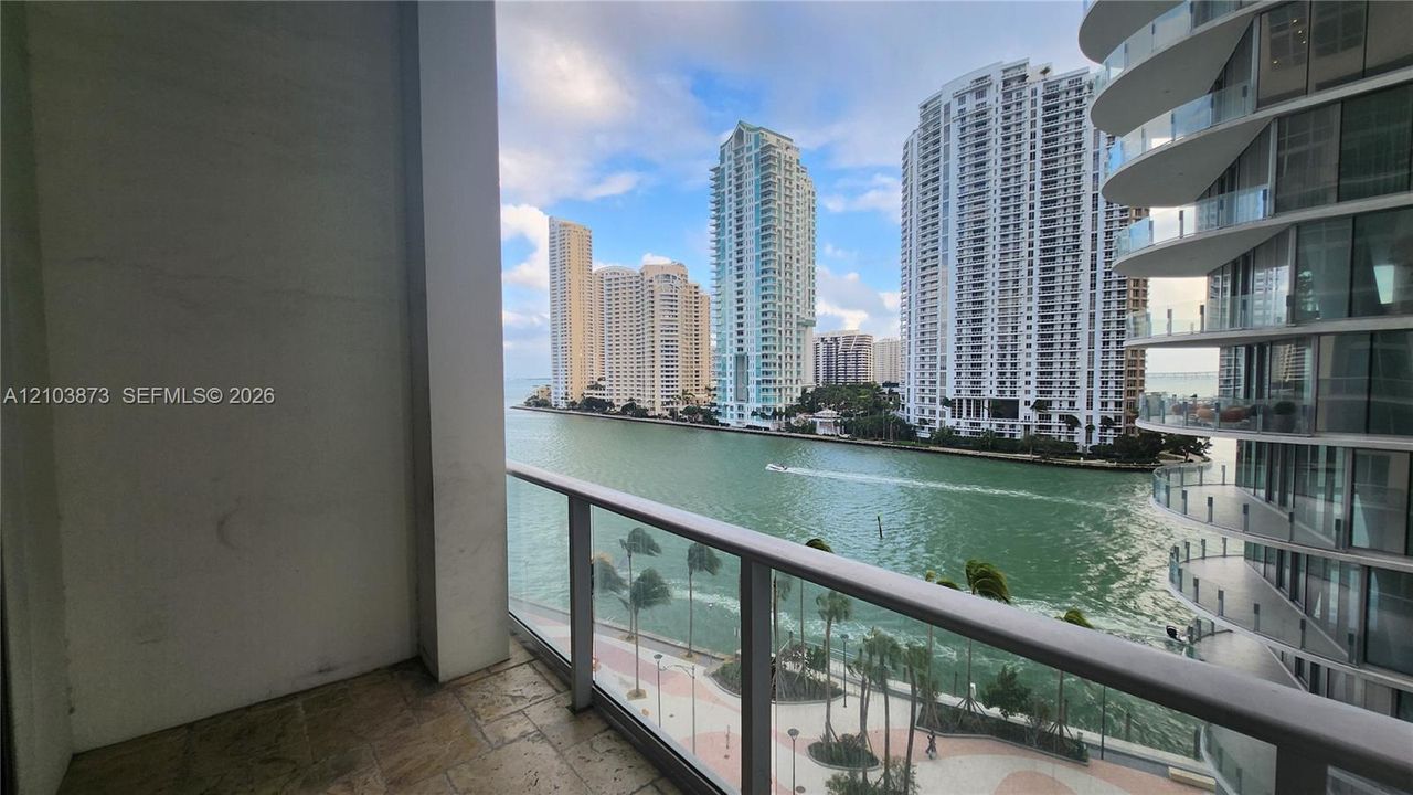 Private balcony featuring stone tile flooring and a glass railing
