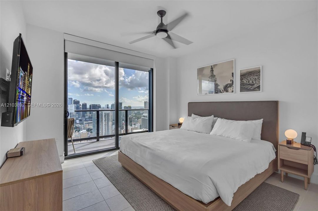 Floor-to-ceiling sliding glass door, private balcony with metal railing, tile flooring, and ceiling fan