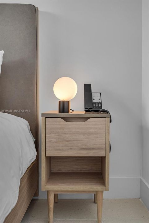 Wood-finish nightstand with integrated drawer storage, open lower shelving, and tapered legs