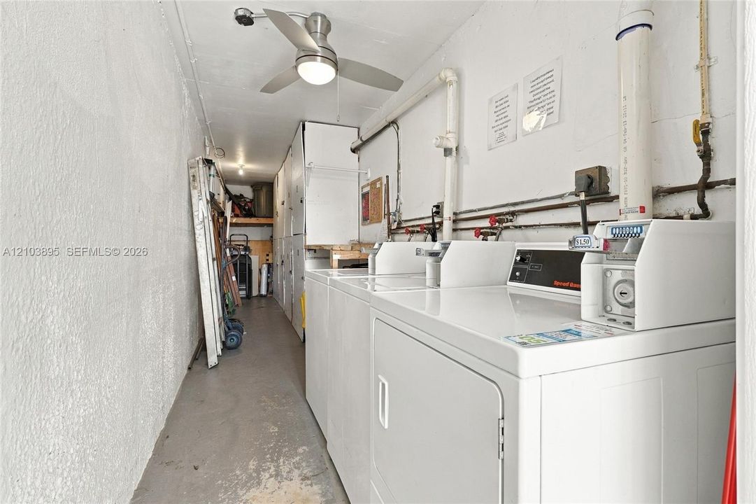 Laundry area featuring built-in coin-operated appliances, unit storage closet, industrial ceiling fan, and concrete flooring