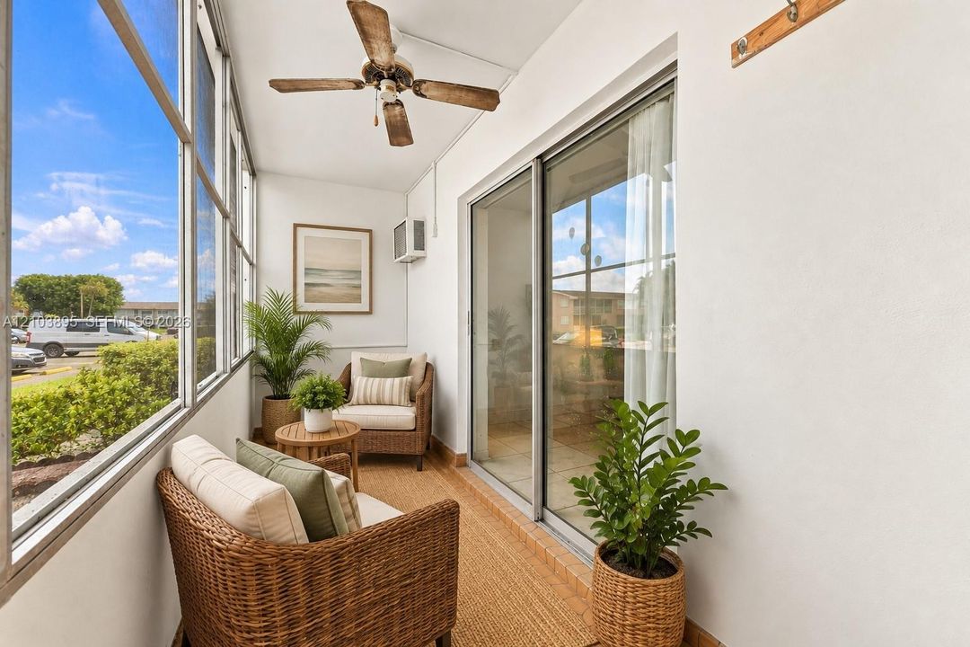 Enclosed sunroom with sliding glass doors, a ceiling fan with wood-finish blades, and wall-mounted hardware