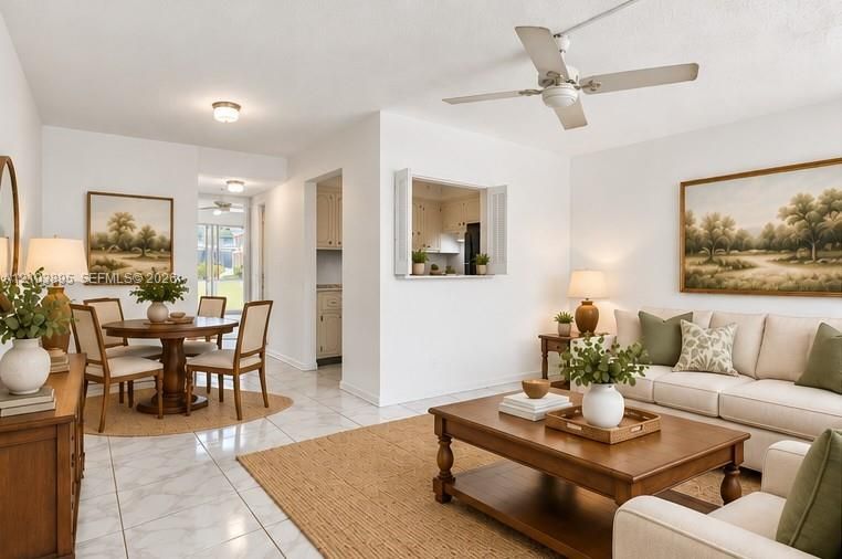 Open-concept interior featuring tile flooring, neutral walls, a pass-through window to the kitchen, and a white ceiling fan
