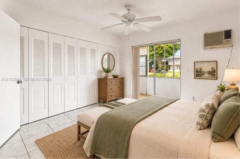 Room featuring tile flooring, a multi-panel floor-to-ceiling closet with louvered doors, a ceiling fan, and sliding glass doors
