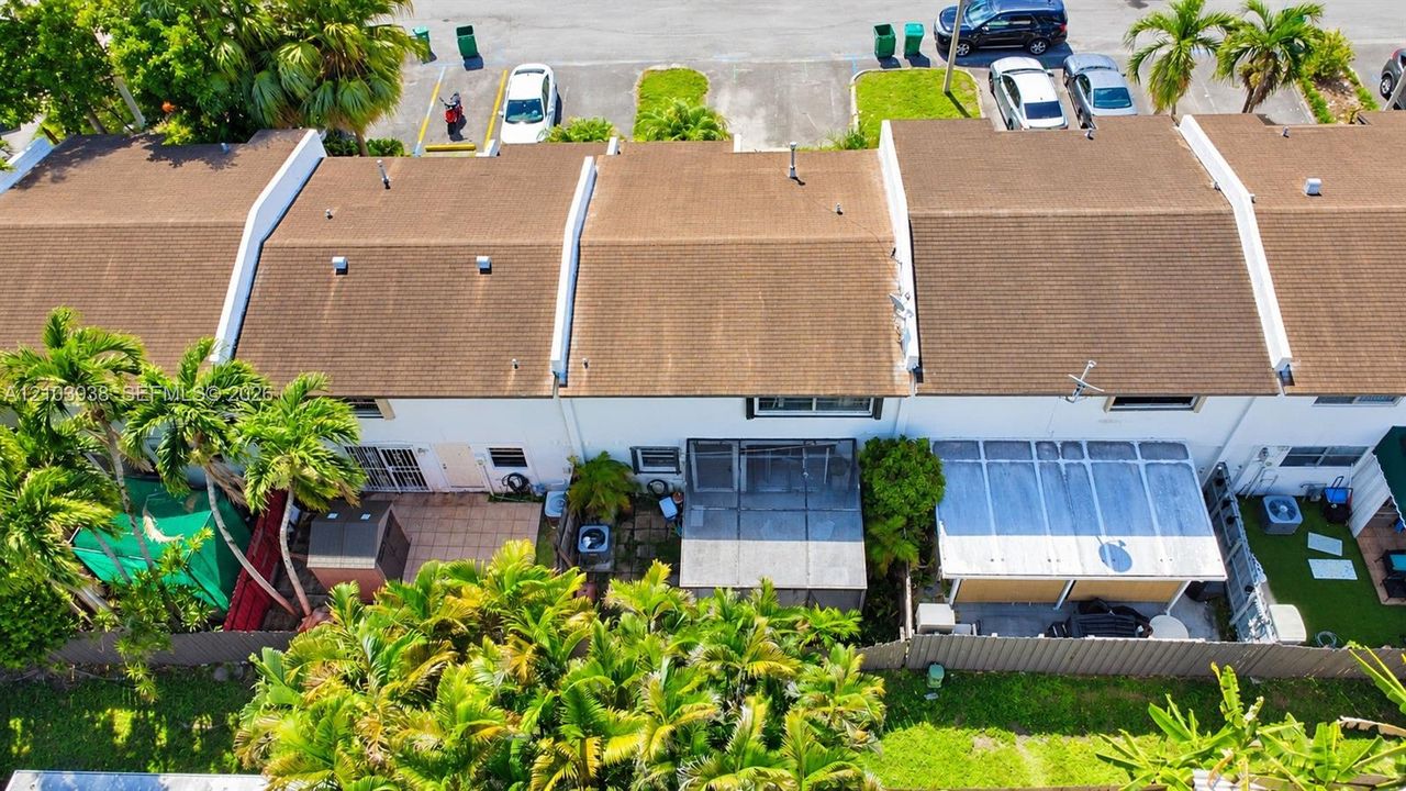 Aerial perspective of townhomes featuring shingled rooflines, exterior patios, screened-in enclosures, and lush perimeter landscaping