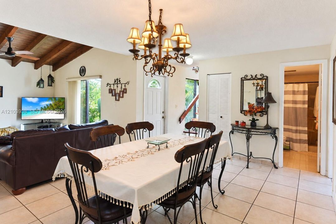 Dining area featuring tile flooring, a multi-arm metal chandelier, and a vaulted ceiling with exposed wood beams
