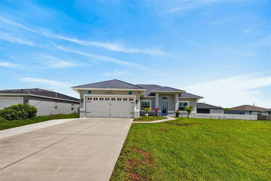 Modern exterior with a tiled roof, attached two-car garage, concrete driveway, and established lawn