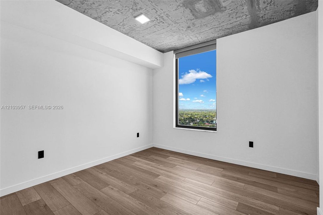 Expansive window, concrete ceiling, wood-finish flooring, recessed lighting, and white walls