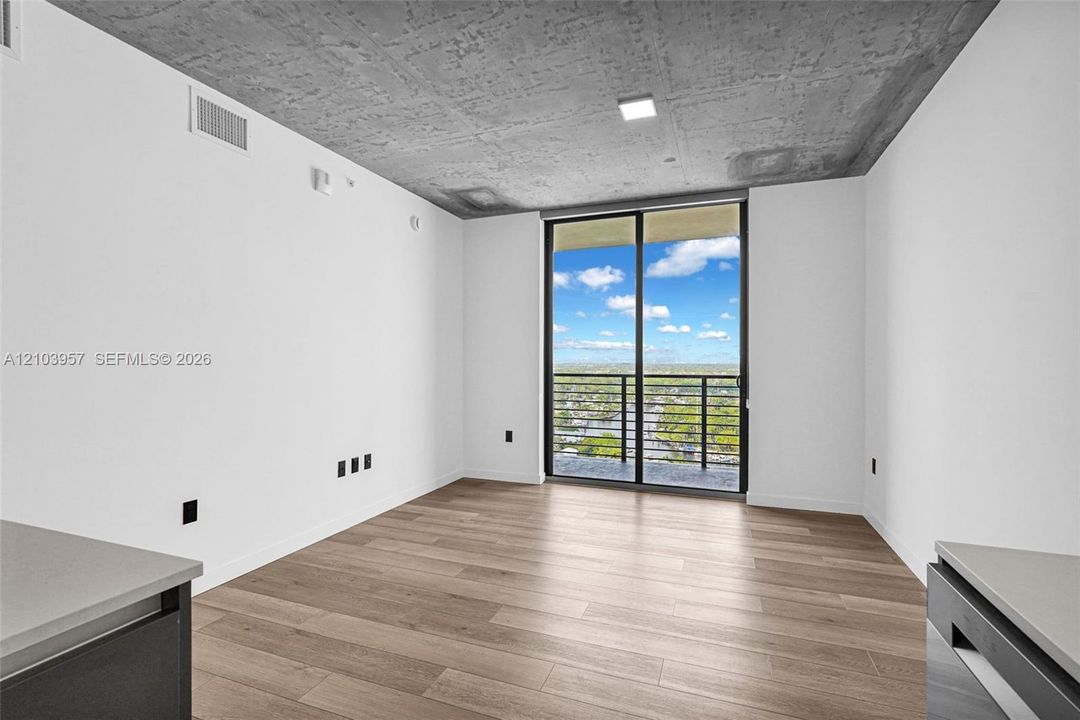 Wood-finish flooring, white walls, and an exposed concrete ceiling