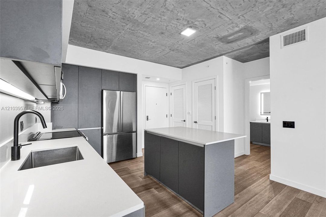 Kitchen featuring a center island, white countertops, dark gray cabinetry, stainless steel appliances, and wood-finish flooring