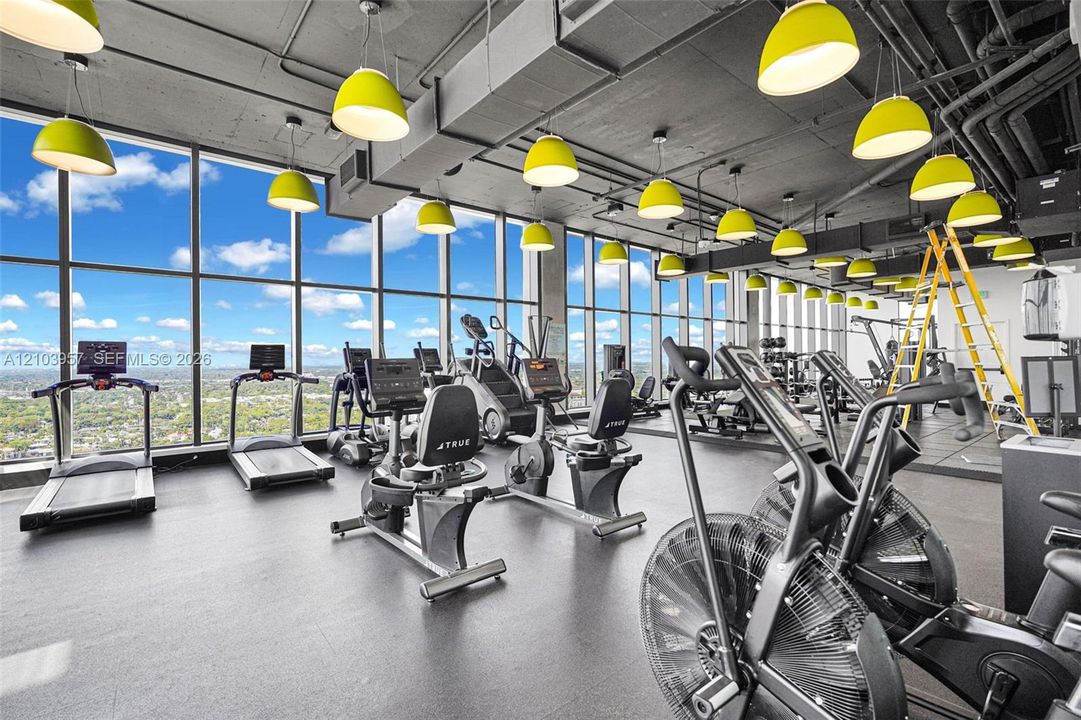 Floor-to-ceiling windows, exposed structural ceiling, high-level urban scenery, suspended pendant lighting, and durable flooring