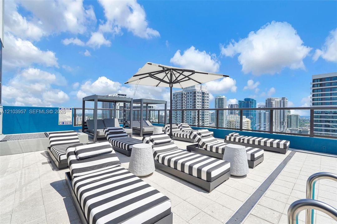 Rooftop deck featuring a glass railing, tiled flooring, and a contemporary cityscape backdrop
