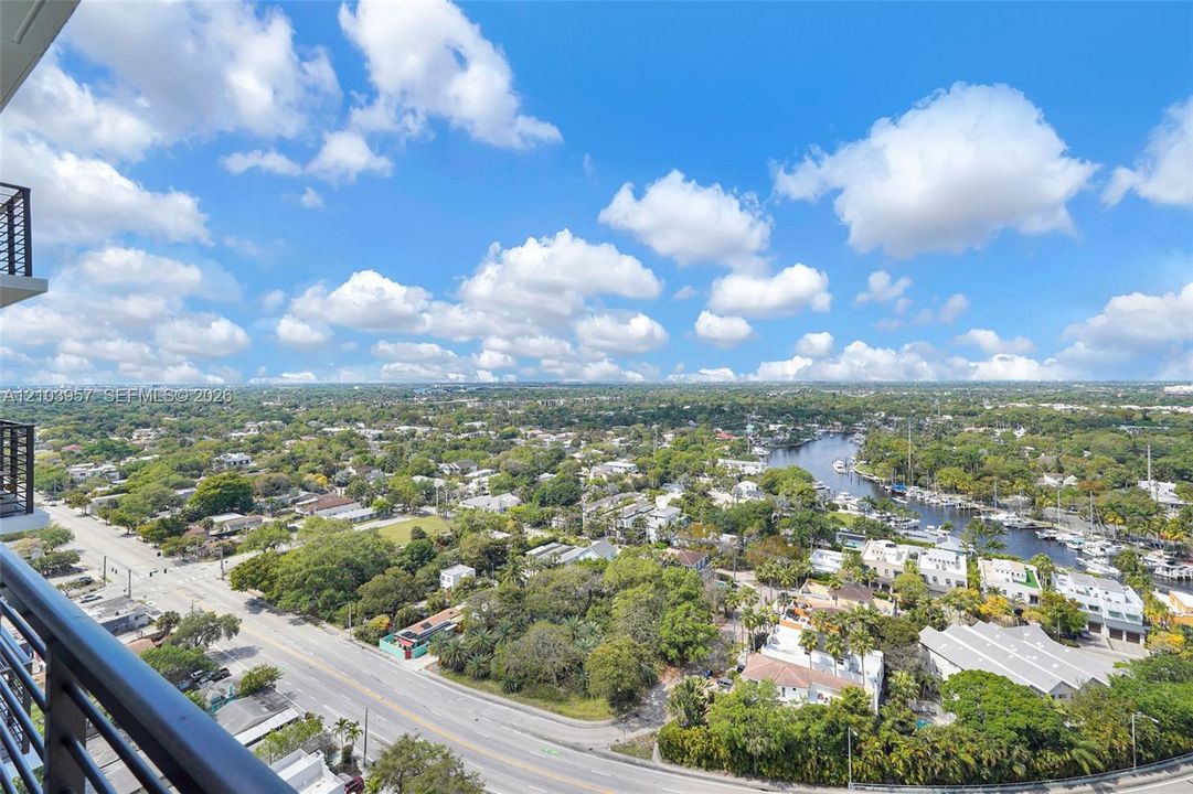 Expansive city and waterway backdrop with established trees and residential structures