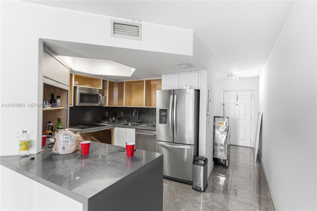 Kitchen featuring a solid-surface peninsula, stainless steel appliances, and tile flooring