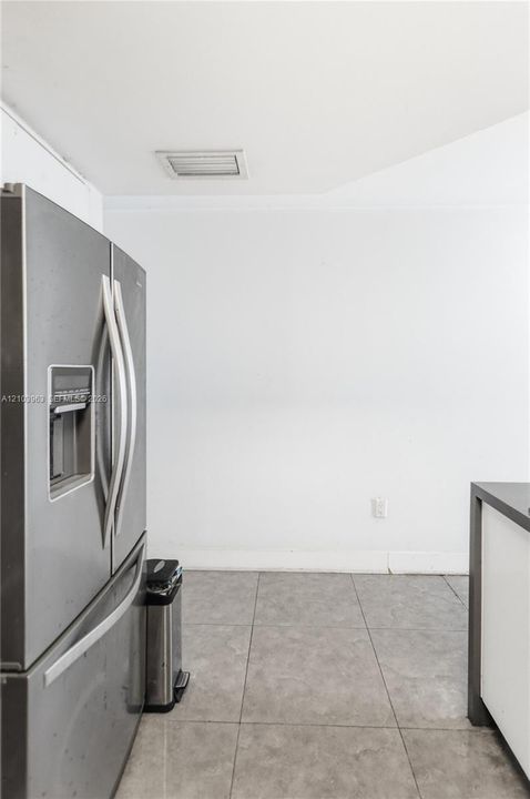 Stainless steel French door refrigerator with an integrated water dispenser and large-format tile flooring