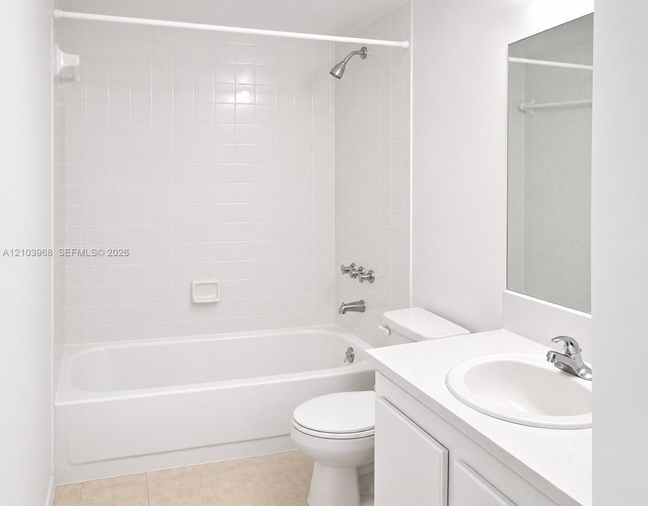 Bathroom featuring a white bathtub with tile surround, a built-in vanity with a sink, a polished finish countertop, and a wall-mounted mirror