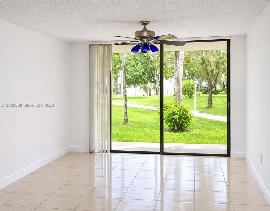 Neutral tile flooring, sliding glass door with vertical blinds, and a multi-light ceiling fan
