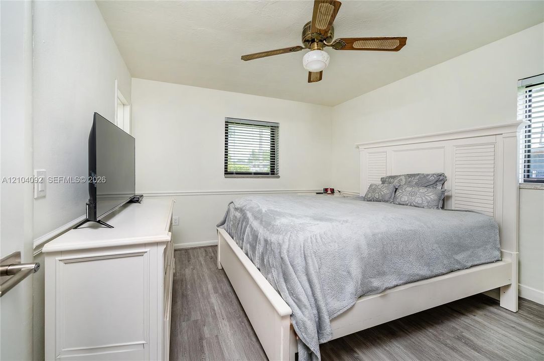 Wood-finish flooring, white wall wainscoting, and a ceiling-mounted fan with integrated light fixture