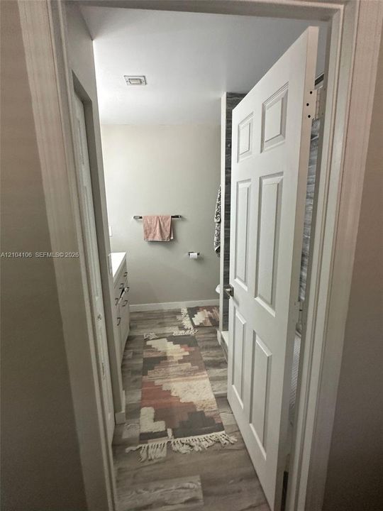 Bathroom featuring wood-finish flooring, a white six-panel door, and vanity cabinetry with metallic hardware