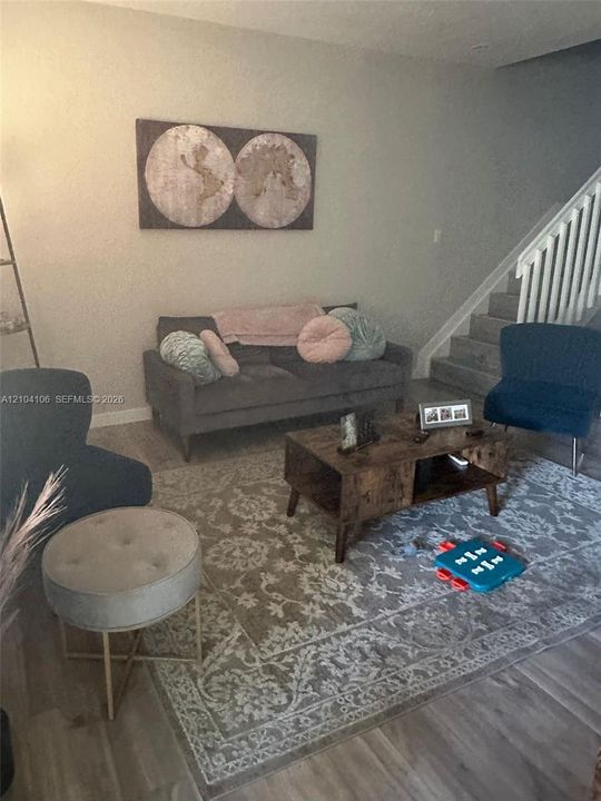 Wood-finish flooring, neutral wall tones, and staircase featuring white vertical balusters