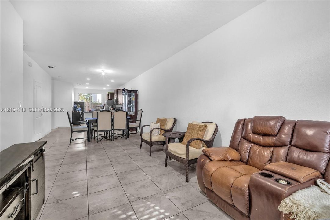 Open-concept living space with tile flooring throughout, white walls, and recessed lighting