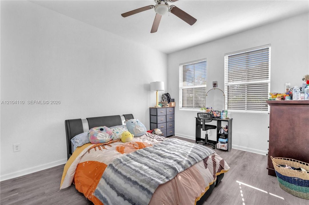 Wood-finish flooring, white walls, and a ceiling fan with integrated lighting
