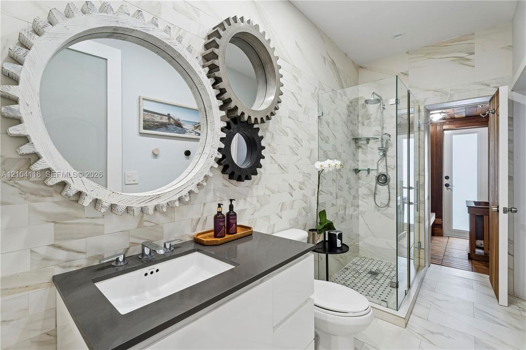 Modern bathroom featuring a single vanity with a white rectangular undermount sink, dark countertop, and chrome faucet