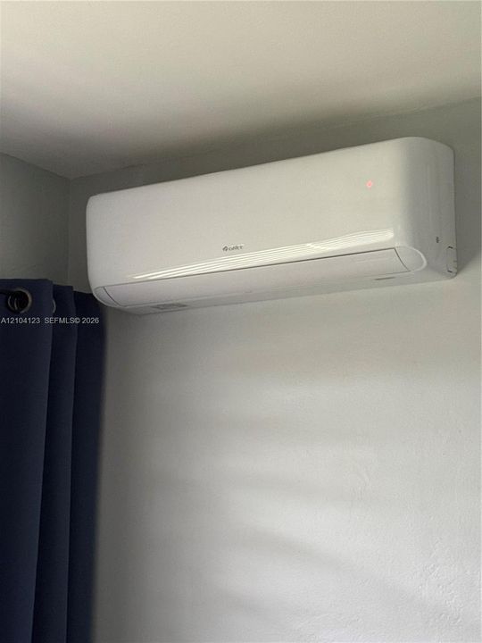 Wall-mounted ductless mini-split climate control system with a white finish in the bedroom