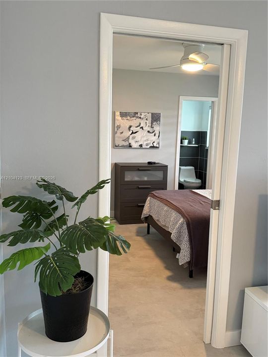 Neutral-toned room featuring a white ceiling fan with integrated lighting and solid-surface flooring