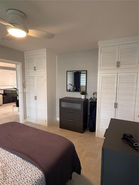 Built-in white louvered cabinetry with brushed metal hardware and a ceiling-mounted light fixture with an integrated fan