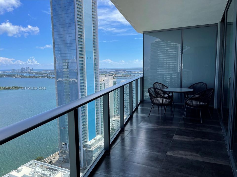 Private balcony featuring large-format tile flooring and a glass panel railing
