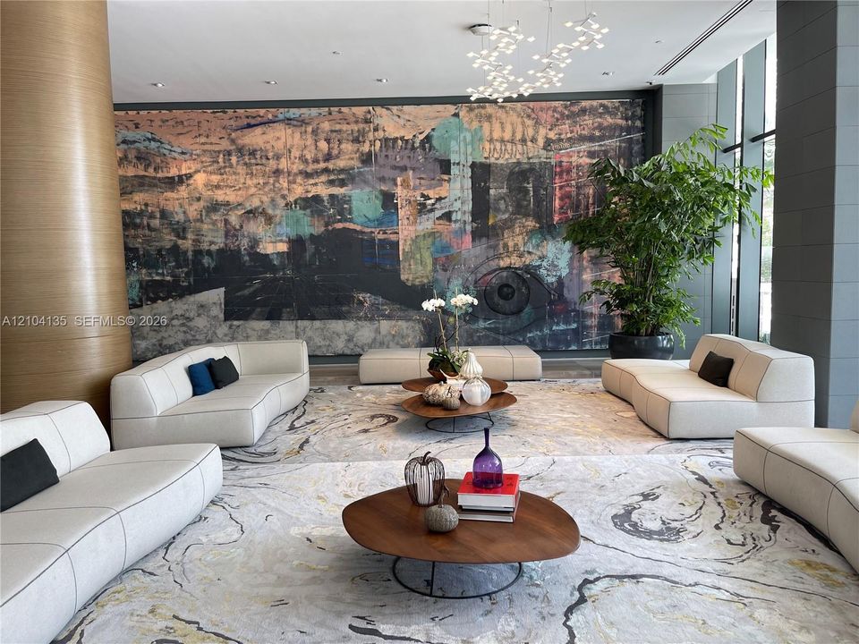 Lobby featuring floor-to-ceiling accent wall, multi-tiered sculptural light fixture, and floor-to-ceiling windows
