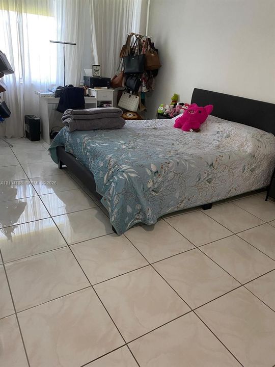 Glossy porcelain tile flooring and large window with floor-to-ceiling sheer drapery