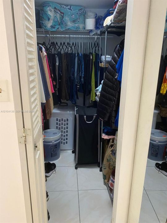 Storage closet featuring white ceramic tile flooring, wire shelving, and louvered bifold doors