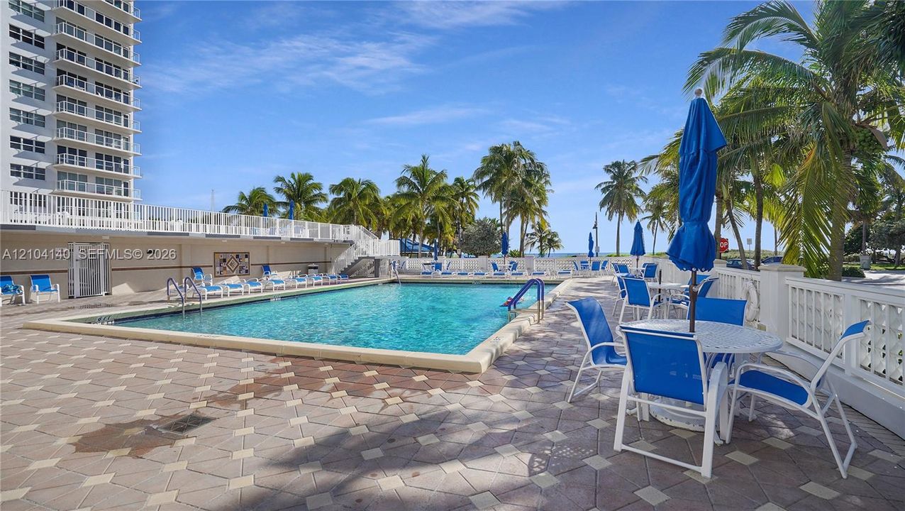 Swimming pool with a paved deck, white balustrade fencing, and mature palm trees