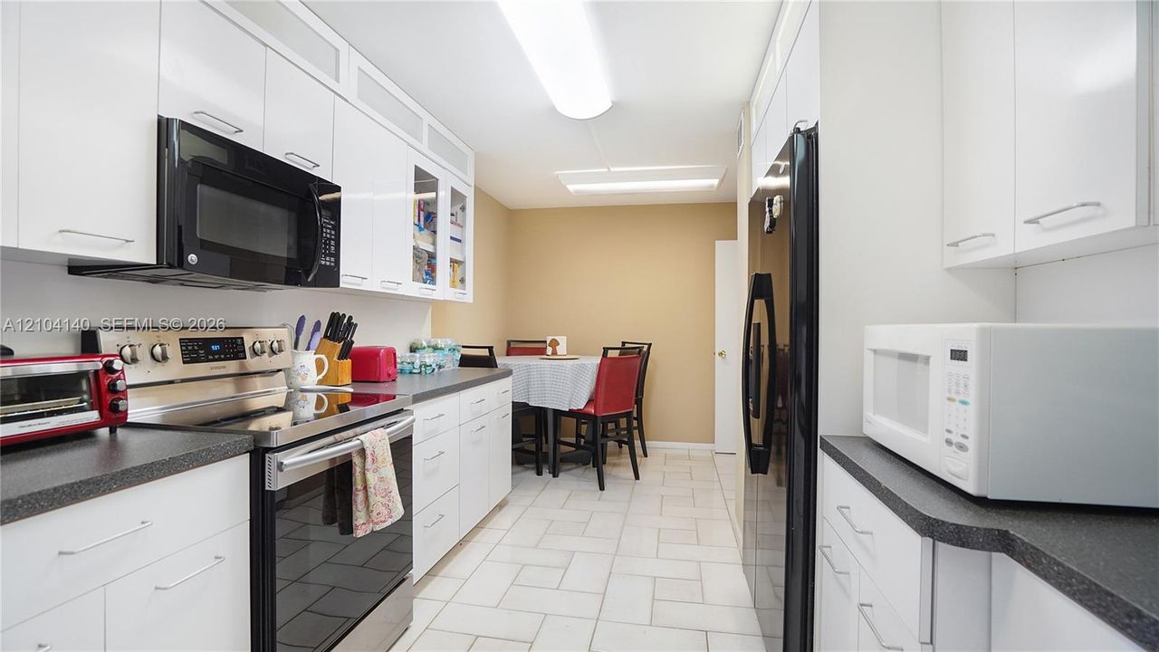 Kitchen featuring white cabinetry, solid-surface countertops, tile flooring, and stainless steel appliances