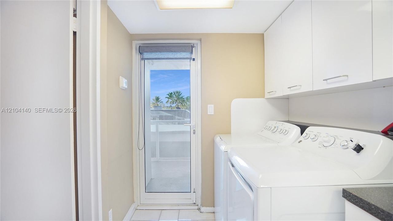 Laundry space featuring white flat-panel upper cabinetry, tile flooring, and a glass-paneled exterior door