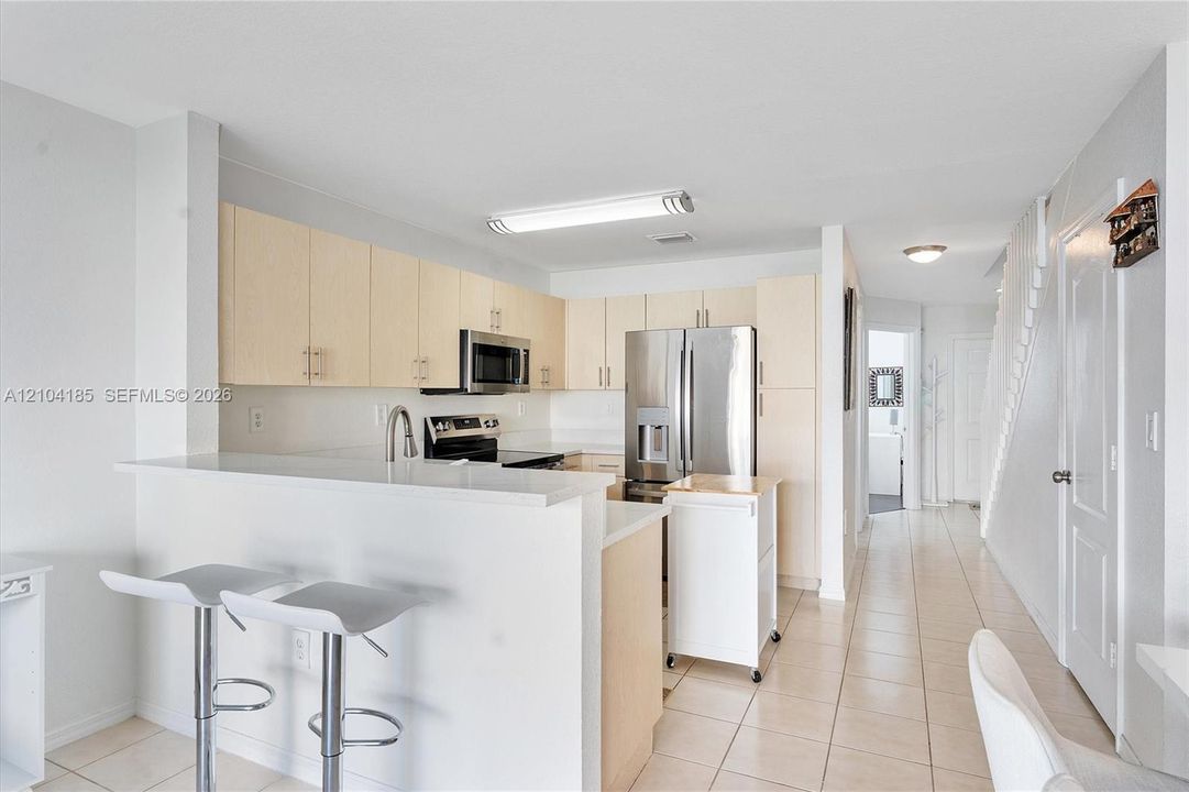 Kitchen featuring light-finish cabinetry, stainless steel appliances, a breakfast bar, and tile flooring