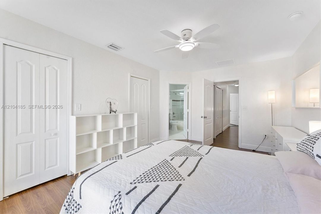 Room featuring wood-finish flooring, white paneled interior doors, and a ceiling-mounted light fixture with an integrated fan
