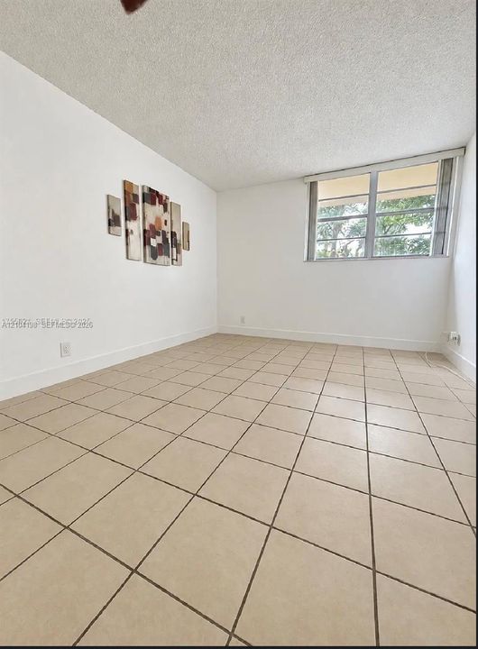 Neutral-toned ceramic tile flooring, textured ceiling, and a large horizontal window with metal frame