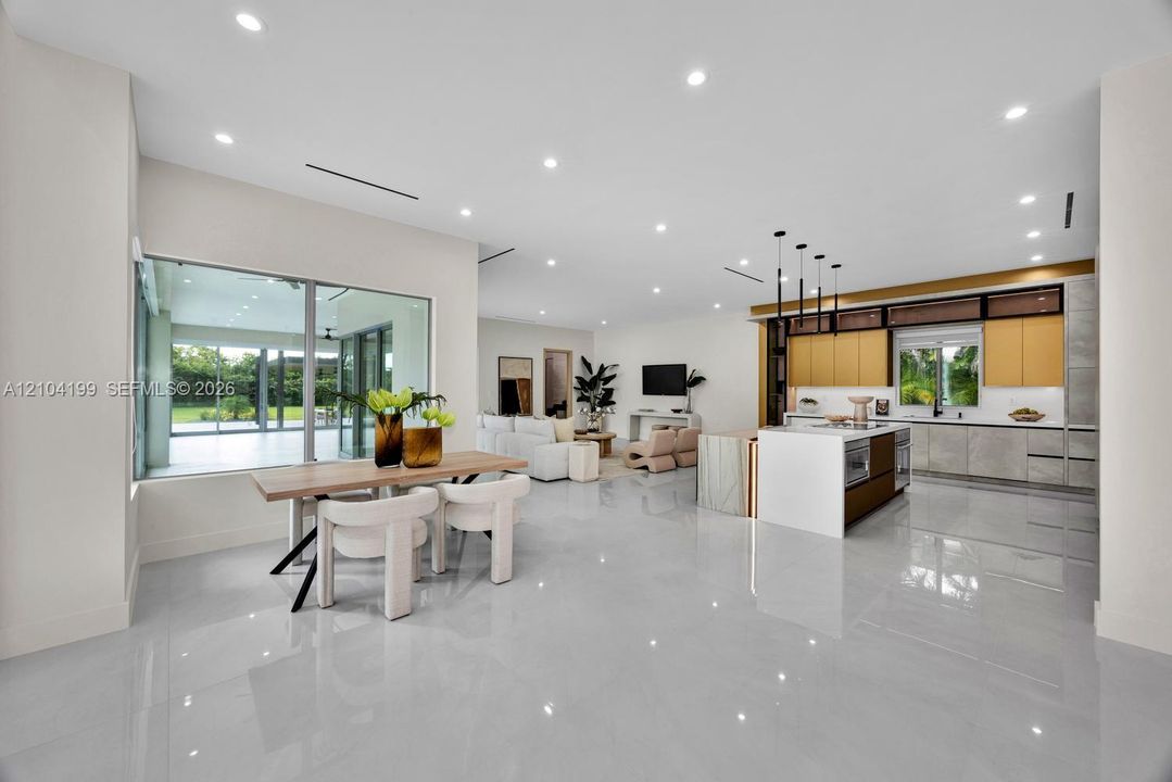 Open-concept interior featuring large-format tile flooring, recessed lighting, and a kitchen equipped with a central island and contemporary flat-panel cabinetry