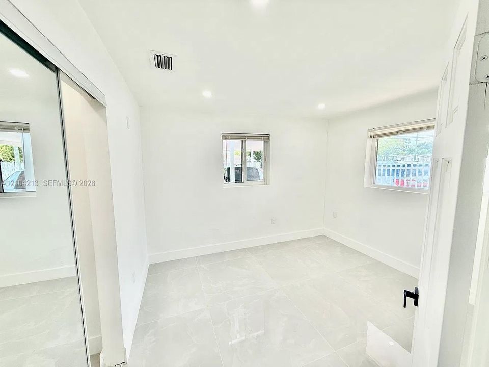 Recessed lighting illuminates the white walls and light-toned tile flooring