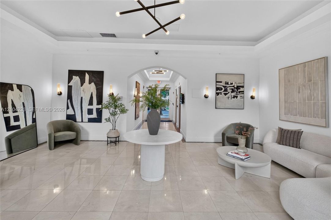 Polished tile flooring, tray ceilings, recessed arched entry, contemporary geometric chandelier, and wall-mounted sconces
