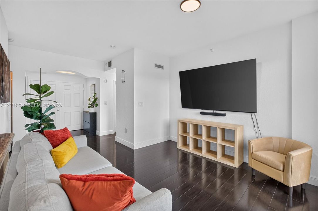 Living area featuring dark wood-finish flooring, crisp white walls, and a recessed ceiling lighting fixture