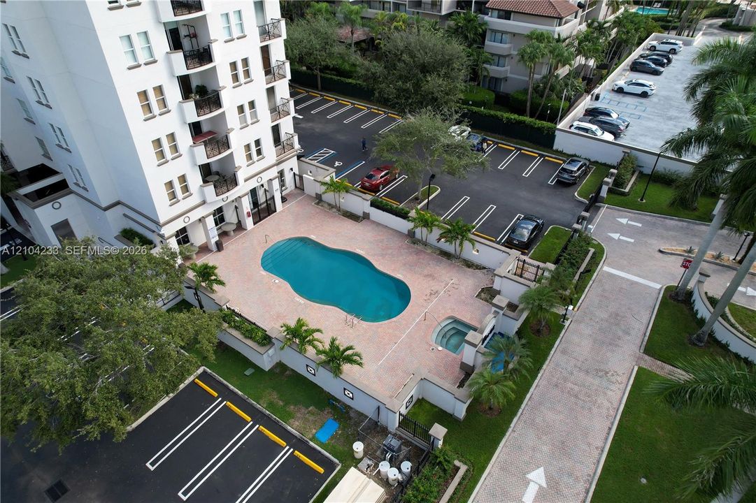 Multi-story exterior featuring a paved pool deck, custom-shaped swimming pool, attached spa, and structured parking area