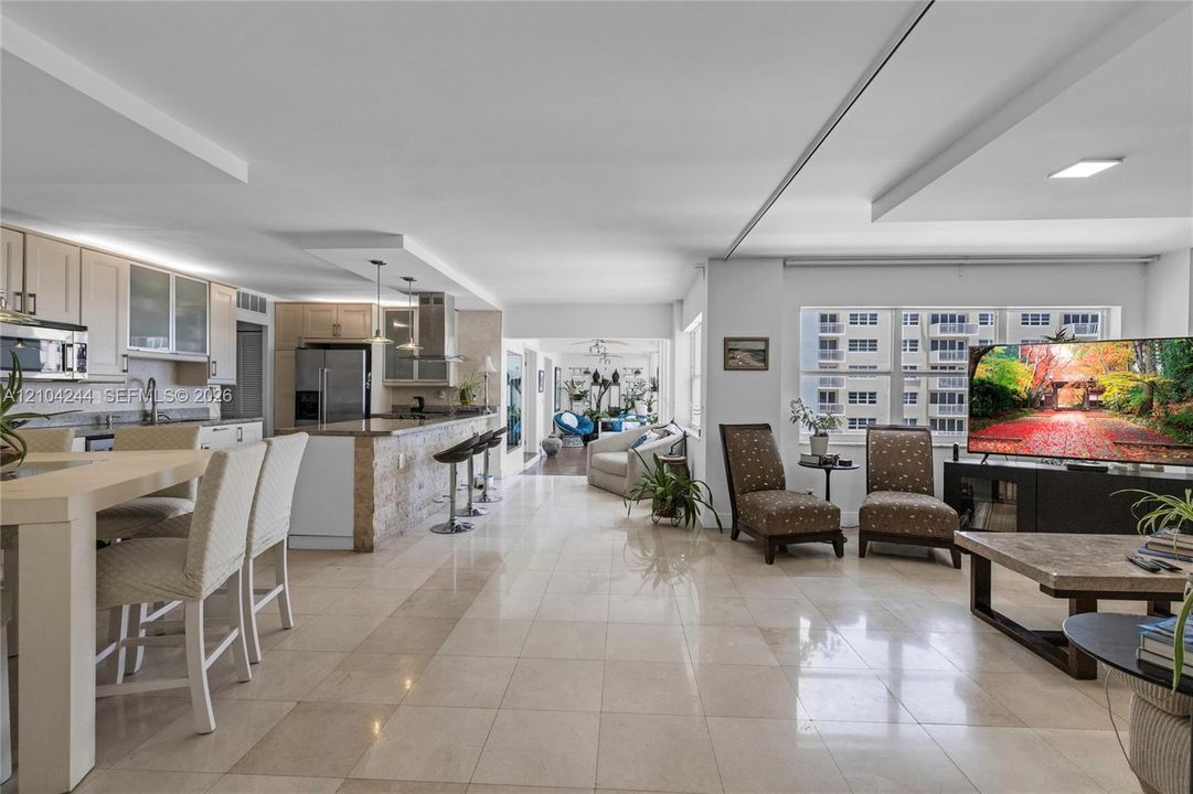 Open-concept layout featuring stone tile flooring, a kitchen island with stone cladding, and large windows