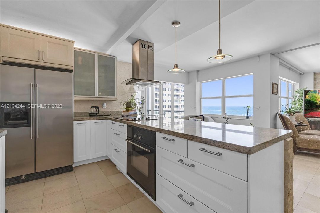 Kitchen featuring stone countertops, stainless steel appliances, a stainless steel range hood, glass-front cabinetry, and pendant lighting