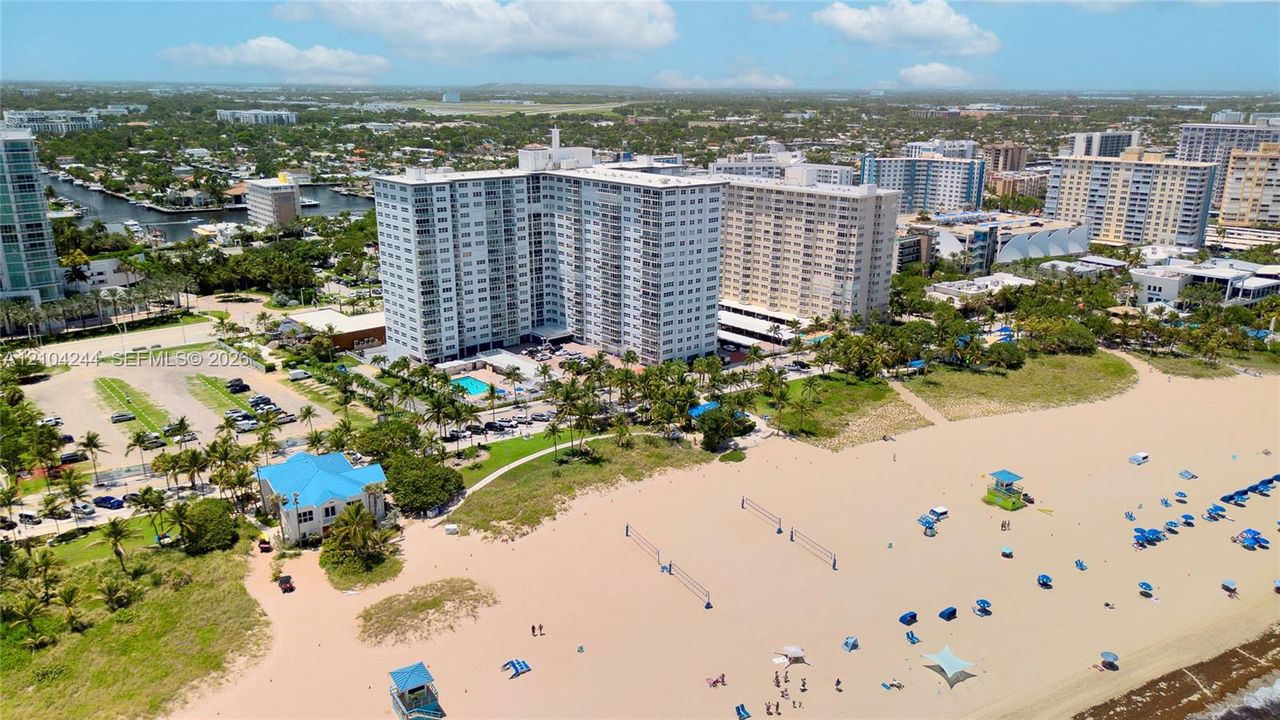 High-rise residential complex featuring direct beach access, an outdoor swimming pool, and proximity to expansive sandy shoreline