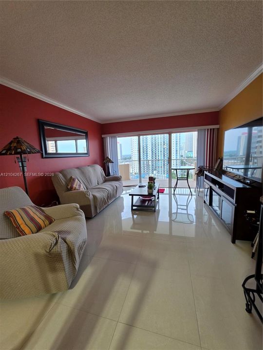 Large-format tile flooring, crown molding, and sliding glass doors opening to a private balcony